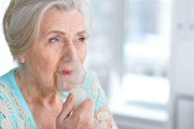 sick senior woman making inhalation