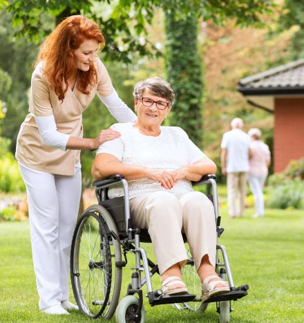 elder woman on wheelchair and caregiver smiling